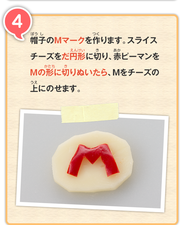 4 帽子のMマークを作ります。スライスチーズをだ円形に切り、赤ピーマンをMの形に切りぬいたら、Mをチーズの上にのせます。