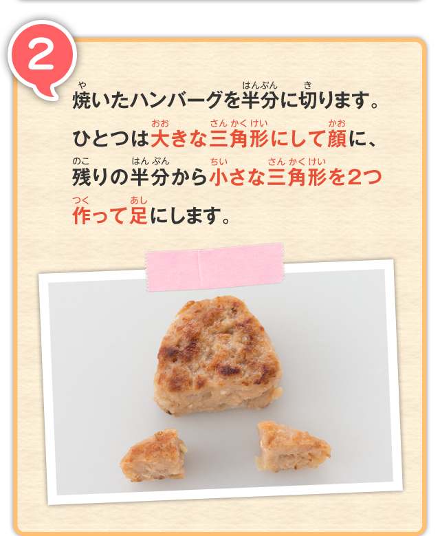 2 焼いたハンバーグを半分に切ります。ひとつは大きな三角形にして顔に、残りの半分から小さな三角形を2つ作って足にします。